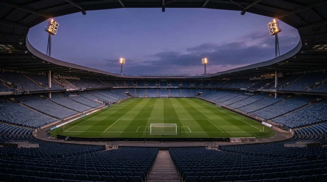 An empty football stadium with floodlight masts at dusk
