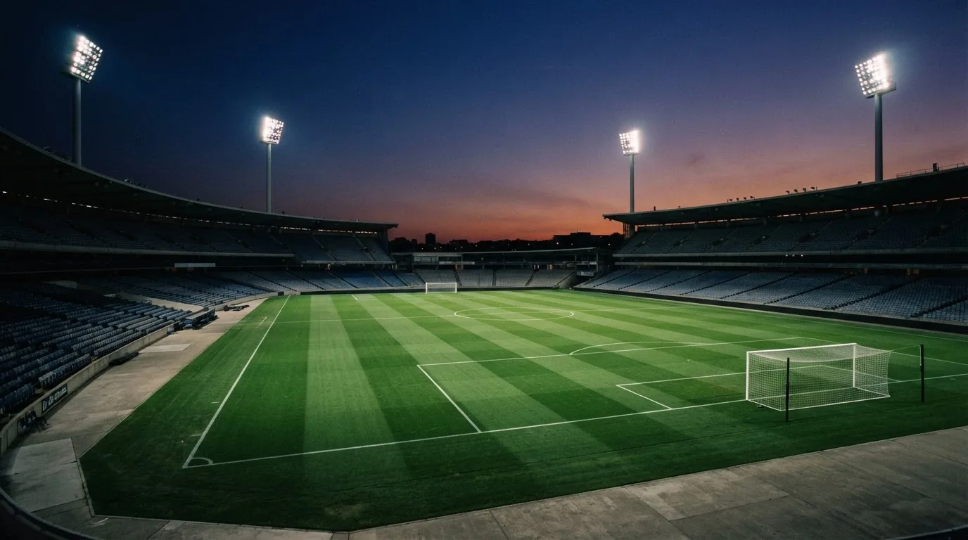 An empty football stadium with floodlight masts at dusk
