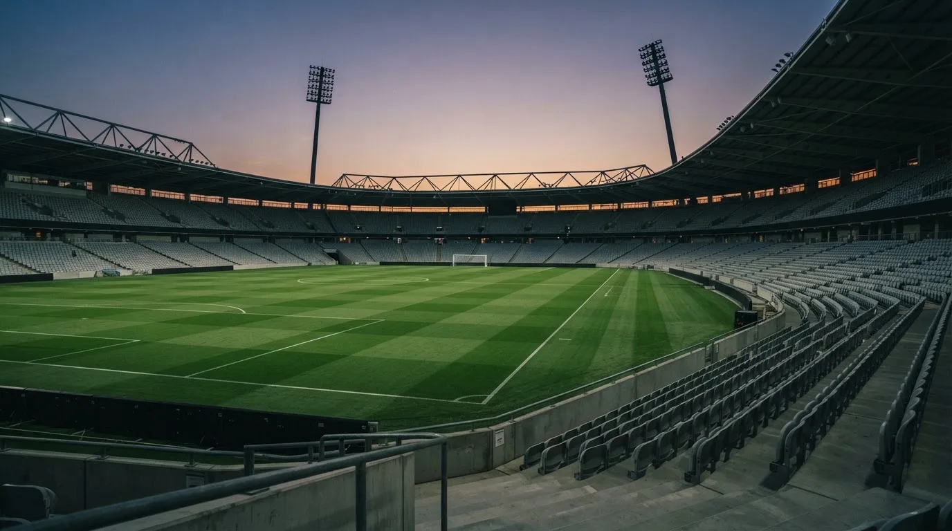 An empty football stadium with floodlight masts at dusk