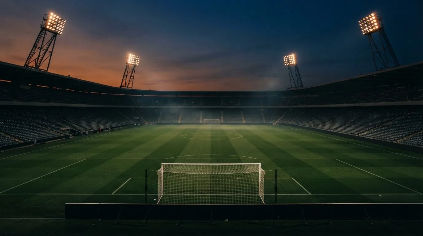 An empty football stadium with floodlight masts at dusk
