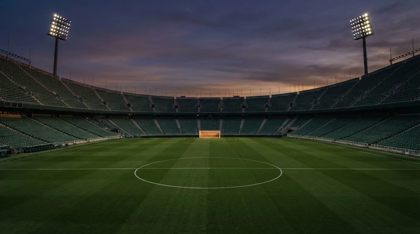 An empty football stadium with floodlight masts at dusk