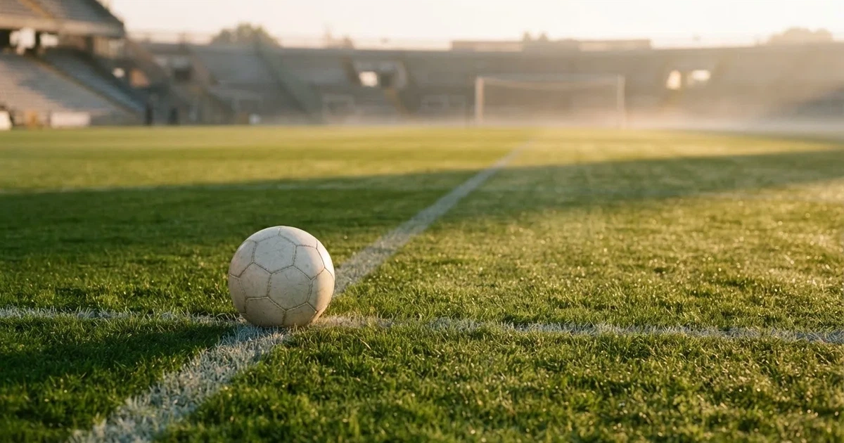 A ball on the centre spot of a grass pitch in morning light